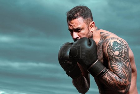Téléchargez les photos : Boxer entraînement en plein air. boxeur masculin entraînement défense et attaques dans des gants de boxe. Punch de boxe - en image libre de droit