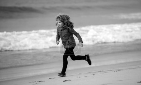 Téléchargez les photos : Un enfant court au bord de la mer. Des enfants qui courent sur la plage. Enfant coureur joggeur courir dans la nature. Mode de vie sain et actif des enfants - en image libre de droit