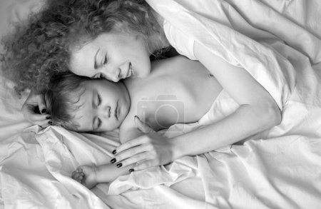 Téléchargez les photos : Mère et bébé dorment dans le lit. Matin de famille dans la chambre - en image libre de droit