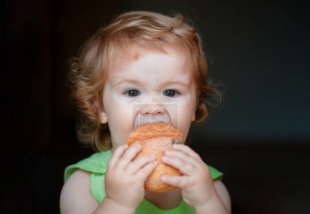 Photo for Portrait of funny baby with bread in her hands eating. Cute toddler child eating sandwich, self feeding concept - Royalty Free Image