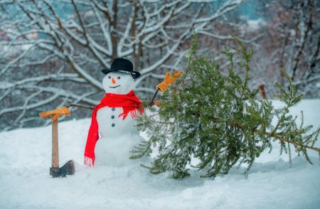 Téléchargez les photos : Bûcheron bonhomme de neige avec hache dans la forêt d'hiver. SnowMan va couper un sapin de Noël. Bonhomme de neige avec hache porte arbre de Noël dans le bois - en image libre de droit