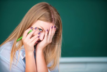Photo for Portrait of young female college shame embarrassed student classroom on class with blackboard background - Royalty Free Image