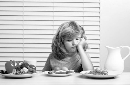 Foto de Portrait of kid with no appetite. Concept of loss of appetite. Child eats organic food. Healthy vegetables with vitamins. Proper kids nutrition concept - Imagen libre de derechos