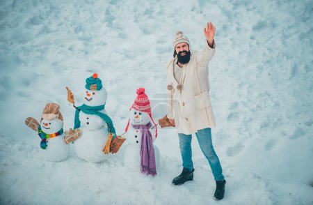 Photo for Merry Christmas and Happy Holidays. Holly jolly swag Christmas and noel. Joyful Handsome young hipster Having Fun with snowman in Winter Park - Royalty Free Image
