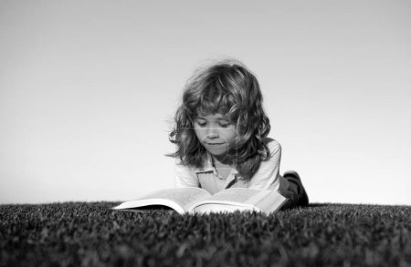 Foto de Retrato al aire libre de un niño inteligente leyendo un libro - Imagen libre de derechos