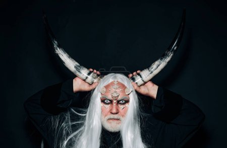 Photo for Demon with bloody horns on head. Devil horns. Devil horror concept. Wizard demon man with dragon skin and horns. Mysterious warrior enchanted to have thorns on his face - Royalty Free Image