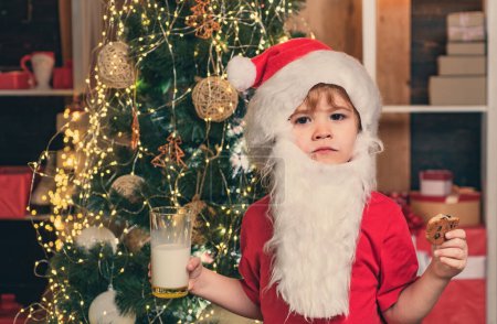 Photo for Santa boy child eating cookies and drinking milk. Christmas cookies and milk. Christmas child. Santa Claus eating cookies and drinking milk on Christmas Eve - Royalty Free Image