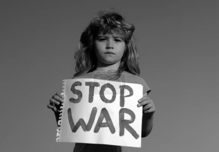Téléchargez les photos : L'enfant porte un signe Stop à la guerre. Portrait petit garçon appelle à arrêter la guerre, lève bannière avec inscription arrêter la guerre. Enfant dans une manifestation avec drapeau ukrainien et affiche Stop guerre - en image libre de droit