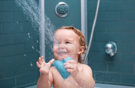 Téléchargez les photos : Bain bébé souriant. Enfant heureux avec de la mousse de savon sur la tête. Enfant drôle sous la douche - en image libre de droit