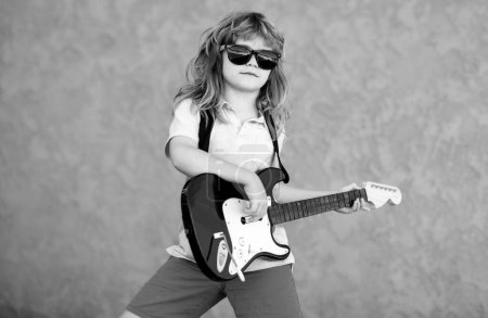 Foto de Niño con guitarra. Niño toca una guitarra y canta, niños música y canción. Niño músico guitarrista tocando la guitarra eléctrica - Imagen libre de derechos