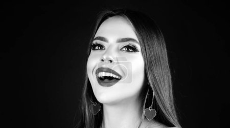 Foto de Hermosa chica feliz. Joven mujer sonriente con maquillaje en estudio negro. Retrato de moda de modelo femenino con labios rojos - Imagen libre de derechos