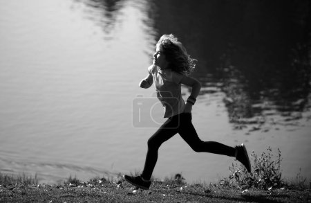 Foto de Niños corriendo al aire libre. Corredor de niños corriendo en la naturaleza. Correr por la mañana. Estilo de vida activo para niños sanos. Una infancia activa y enérgica. Correr movimiento - Imagen libre de derechos