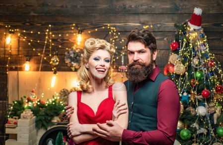 Photo for Happy Christmas couple in evening dress with red gift box over home Christmas tree background. Fashion and beauty make-up and hairstyle for Christmas - Royalty Free Image