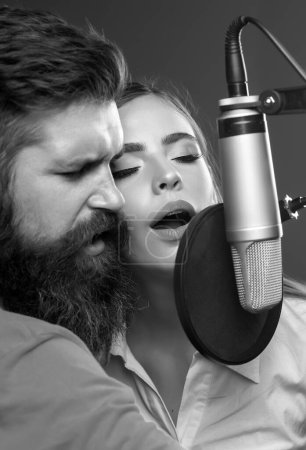Téléchargez les photos : Couple en studio d'enregistrement. Performance musicale vocale. Chanteur chantant chanson avec un microphone - en image libre de droit