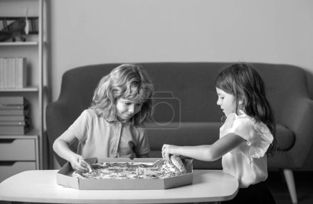 Photo for Cute little boy and girl eating Pizza at home. Children holding a slices of pizza on party at home. Children sharing a pizza together - Royalty Free Image