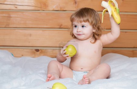 Téléchargez les photos : Nourriture solide pour bébé. Enfant avec des fruits frais pomme et banane. Légumes et fruits frais - en image libre de droit
