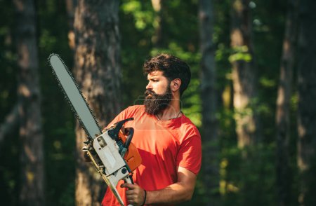 Photo for Woodcutter with chainsaw on sawmill. Woodworkers lumberjack. Man doing mans job. Woodcutter with axe or chainsaw in the summer forest. Illegal logging continues today - Royalty Free Image