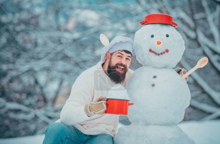 Foto de Chef de Navidad. Hombre con muñeco de nieve en la cocina de invierno. Guapo Santa Claus cocinero - Imagen libre de derechos