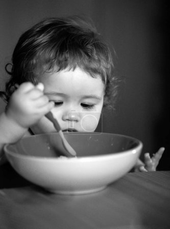 Photo for Happy baby eating himself with a spoon - Royalty Free Image