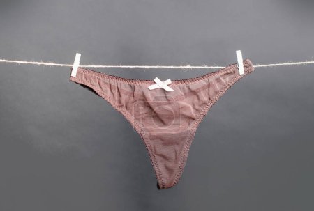 Foto de Panties. Female lace lingerie. Womans erotic underwear panties. Womens panties hanging on rope isolated on gray background - Imagen libre de derechos