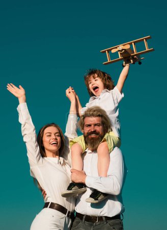 Photo for Happy family outdoor. Parents with child. Boy with toy airplane on fathers shoulders. Motherhood fatherhood. Son father and mother - Royalty Free Image