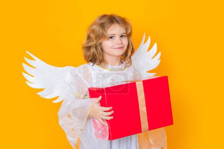 Photo for Cute blonde kid angel with gift box present. Beautiful little angel. Isolated studio shot. Cute Pretty child with angel wings. Cupid, valentines day concept - Royalty Free Image