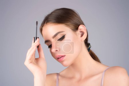 Téléchargez les photos : Eyebrow shaping, woman combs eyebrows with a brus. Eyebrow line. Makeup and cosmetology concept. Female model with long eyelashes and thick eyebrows. Perfect shaped brow - en image libre de droit
