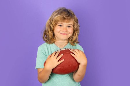Téléchargez les photos : Football américain. Garçon avec balle de rugby. Enfant prêt à lancer un ballon. Concept sport pour enfants. Activités sportives pour enfants, studio isolé - en image libre de droit