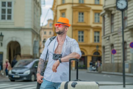 Foto de Viajero, turista de moda. Hombre turista viajero en ropa casual sombrero con maleta. Hombre de negocios turístico que viaja en la ciudad europea. Hombre de negocios rico de confianza que viaja en la ciudad europea - Imagen libre de derechos