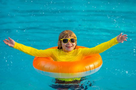 Téléchargez les photos : Vacances d'été. Enfant avec anneau gonflable dans la piscine. Vacances d'été. Vacances d'été. Week-end d'été pour enfants. Enfant dans la piscine. Enfant flottant au bord de la piscine - en image libre de droit