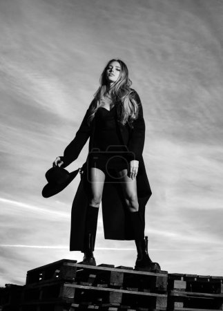 Photo for Sexy woman in black fashion coat, hat and black shoes boots. Fashionable young model in style dress. Fashion woman in summer - Royalty Free Image