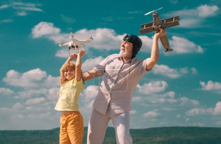 Téléchargez les photos : Enfant garçon et grand-père avec avion et quadcopter drone sur fond bleu ciel et nuages - en image libre de droit