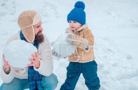 Photo for Happy family plaing with a snowman on a snowy winter walk. Father and son making snowball on winter white background - Royalty Free Image