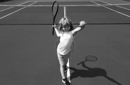 Téléchargez les photos : Enfant garçon jouant au tennis sur le terrain extérieur. Petite fille avec raquette de tennis et ballon dans un club de sport. Exercice actif pour les enfants. Activités estivales pour les enfants. Formation pour les jeunes enfants - en image libre de droit