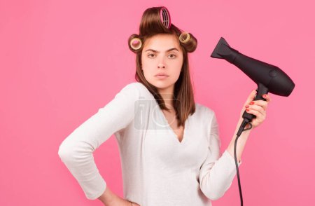Photo for Young funny woman with hair dryer and rollers. Woman with hair dryer. Beautiful girl with straight hair drying hair with professional hairdryer - Royalty Free Image
