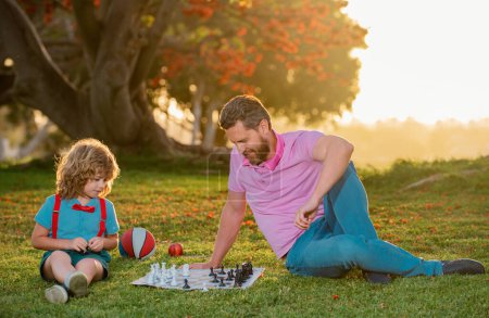 Photo for Father play chess with son. Kids chess school. Family outside game - Royalty Free Image