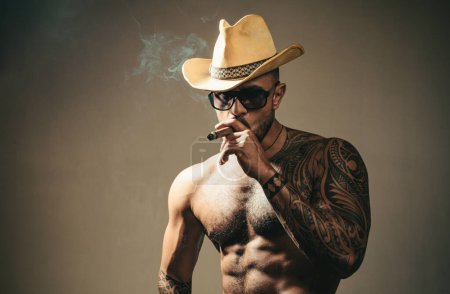 Téléchargez les photos : Visage d'homme sexy. Imposant mec à lunettes fumant cigare. Hommes beauté, portrait de mode - en image libre de droit