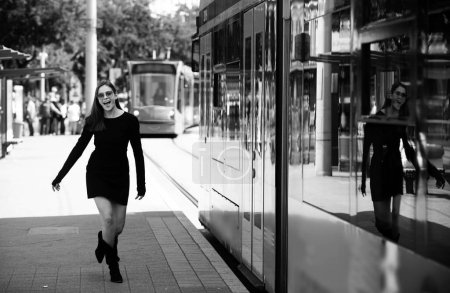 Téléchargez les photos : Femme à la mode courir après trolleybus de bus et tirant trolley cas dans la rue, style de rue de la mode - en image libre de droit
