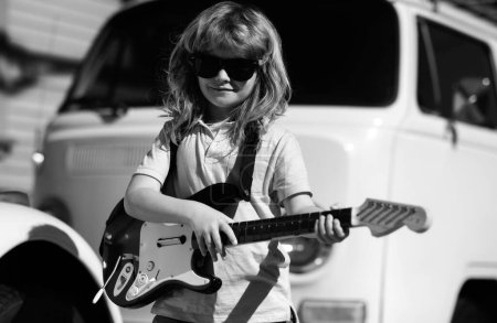 Téléchargez les photos : Instruments de musique pour enfants. Enfant musicien guitariste jouant de la guitare électrique - en image libre de droit