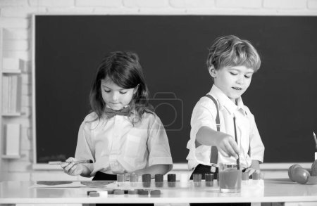 Photo for School children drawing a colorful pictures with pencil crayons in classroom. Portrait of cute pupils enjoying art and craft lesson - Royalty Free Image