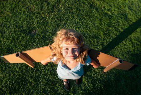 Téléchargez les photos : Joli garçon rêveur jouant avec un avion en carton. Enfance. Fantaisie, imagination - en image libre de droit