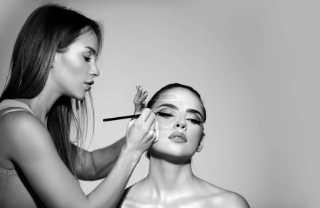 Photo for Beauty makeup. Makeup artist applies eye shadow. Hand of visagiste, painting cosmetics of young beauty model girl. Professional make up process. Fashion and beauty, cosmetics, beauty salon - Royalty Free Image