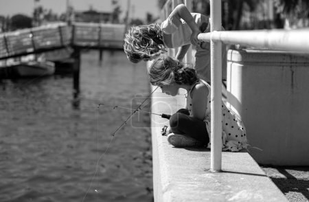 Foto de Dos niños pescando en un río o lago. Feliz emocionado sorprendió a los niños amigos sorprendidos pesca juntos cerca del estanque con cañas de pescado - Imagen libre de derechos