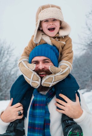 Foto de Papá y el niño sonriendo y abrazándose. Las fiestas navideñas y el invierno un nuevo año con el padre y el hijo. Escena de invierno sobre fondo de nieve blanca - Imagen libre de derechos