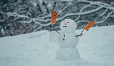 Foto de Hombre de nieve en el parque de invierno. El hombre de la nieve está de pie en el parque de invierno con la nariz roja. Muñecos de nieve divertidos - Imagen libre de derechos