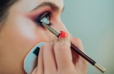 Téléchargez les photos : Concept de maquillage pour les yeux de luxe. Purple smokey yeux maquillage photo de près. Les yeux fumés professionnels se composent à belle fille pour une occasion spéciale. Pigments brillants à paillettes dans le maquillage des yeux - en image libre de droit