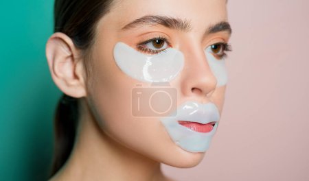 Photo for Healthy beautiful girl with natural makeup applies collagen catches for eyes and lips to make her skin routine and look fresh. Close up portrait of beautiful model doing skin care - Royalty Free Image