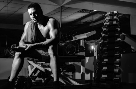 Foto de Musculoso hombre crossfit. Un joven haciendo ejercicio en el gimnasio crossfit. Deportista sin camisa descansando después de entrenar en el gimnasio - Imagen libre de derechos