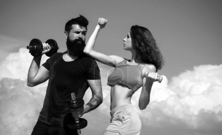Photo for Sportive fitness couple, bearded man and sexy woman working out outdoors, sportive couple training with dumbbells, muscular coupl outdoor. Fitness sexy models pumping up arm with dumbbell - Royalty Free Image