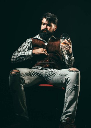 Photo for Hipster with beard and mustache in suit drinks alcohol after working day. Alcohol addict. Man with beard holds glass of brandy - Royalty Free Image